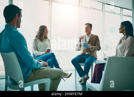 Questo è il punto in cui tutto inizia per l'azienda. Shot di un gruppo di uomini d'affari che prendono appunti durante una riunione in ufficio. Foto Stock