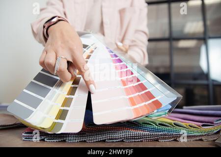 Primo piano mano di donna decoratore interno designer sta scegliendo catalogo colori ral per il progetto. Foto Stock