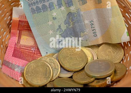 Denaro in un cestino di donazione Foto Stock