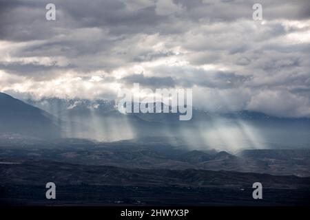 Una luce solare spettacolare che attraversa le nuvole e colpisce le montagne, in uno scenario epico. Foto Stock