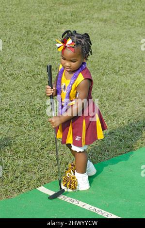 Giovane ragazza in cheerleaders uniforn giocare con Gold Club e la sfera in corrispondenza di fund raising evento per squadre di calcio Foto Stock