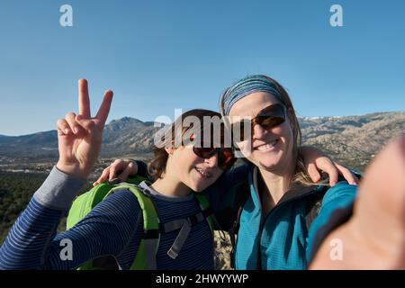 Un ragazzo di teenage con le bretelle e la madre che prende selfie durante le escursioni in natura Foto Stock