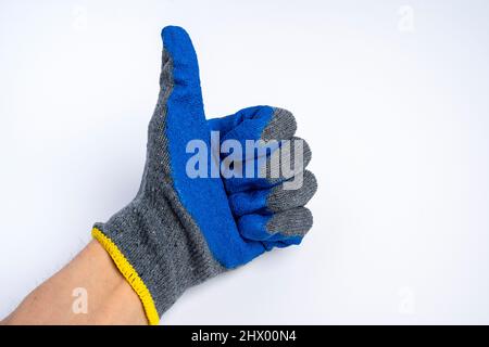 la mano di un uomo in guanti da lavoro in gomma blu mostra un pollice su uno sfondo blu, un barattolo di approvazione Foto Stock