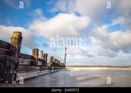 Immagine di lunga esposizione di demolitori di mare o di groynes di legno sulla spiaggia di Cromer sulla costa nord del Norfolk Foto Stock