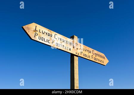 Cartello bilingue in legno su un sentiero pubblico contro un cielo blu profondo. Spazio di copia. Nessuna gente. Foto Stock
