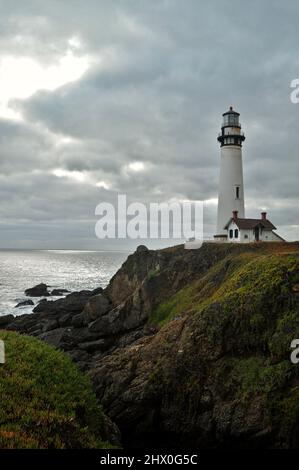 Storico 1871 Coast Guard Pigeon Point Lighthouse al tramonto nuvoloso lungo la costa frastagliata / scogliere che si affacciano sull'Oceano Pacifico, Pescadero, California, Stati Uniti Foto Stock