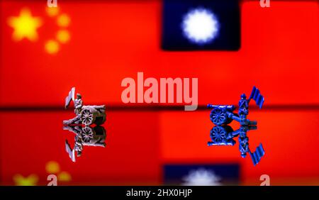Immagine concettuale della guerra tra Cina e Taiwan utilizzando soldati giocattolo e bandiere nazionali su sfondo riflettente Foto Stock