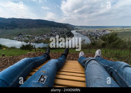 Mehring, Renania- Palatinato - Germania - 04 12 2019 - jeans blu gambe di un giovane uomo e donna che si affaccia sul fiume Meurthe Mosella circondato Foto Stock