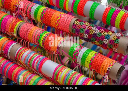 Immagine di un mucchio di braccialetti in pelle con forme e colori diversi esposti in una stalla per la vendita in una fiera di strada Foto Stock