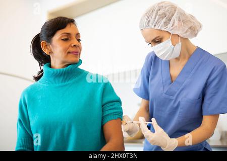 Medico che ha somministrato il vaccino Covid-19 alla paziente femminile Foto Stock