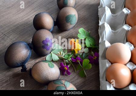 Uova di Pasqua decorate con foglie e fiori, preparate per tinture naturali con bucce di cipolla Foto Stock