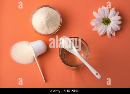 Proteina di collagene in polvere nel cucchiaio. Bicchiere d'acqua Foto Stock