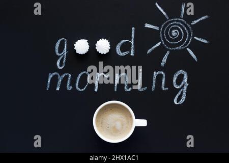 Testo Buongiorno, gesso di sole su sfondo nero, tazza di caffè, meringa. Disposizione piatta, vista dall'alto. Concetto Foto Stock