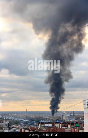 Fuoco in città. Una colonna nera di fumo sale al cielo. Foto Stock