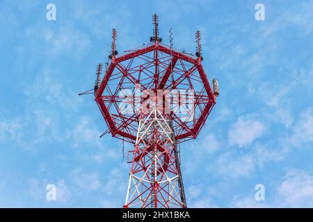 Torre di telecomunicazioni con antenne su sfondo di cielo blu con nuvole. Torre della televisione e della radio in una grande città. Foto Stock