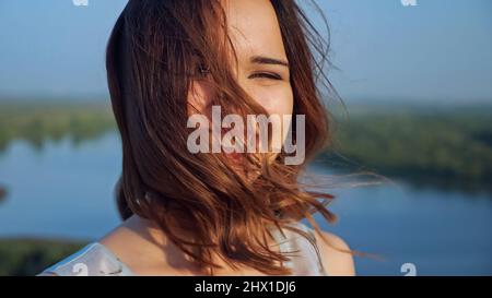 Bella donna con capelli volanti e trucco leggero sulla riva del fiume Foto Stock