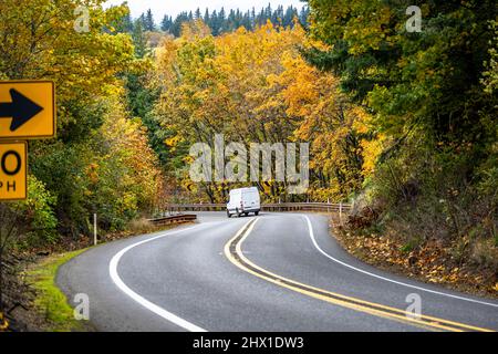 Mini furgone industriale compatto bianco di piccole dimensioni con tetto alto per una consegna locale confortevole e piccole esigenze aziendali in esecuzione sul tortuoso autunno montano Foto Stock