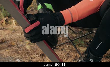 Allenare un atleta sui pattinatori a rulli. Giro in biathlon sugli sci con racchette da sci, nel casco. Allenamento autunnale. Sport rullo. Uomo adulto che guida sui pattini. L'atleta indossa sci e casco. Foto Stock