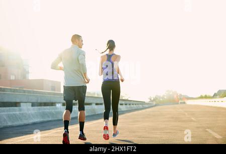 Niente di meglio di una corsa mattutina. Foto con vista posteriore di due amici che jogging attraverso la città. Foto Stock