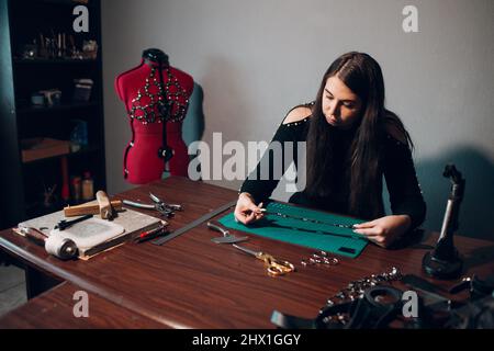 Tanner donna che fa articoli in pelle in officina. Processo di lavorazione del cuoio artigiano. Foto Stock