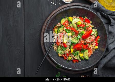Insalata sana con quinoa, verdure ed erbe fresche su sfondo nero. Insalata vegetariana. Foto Stock