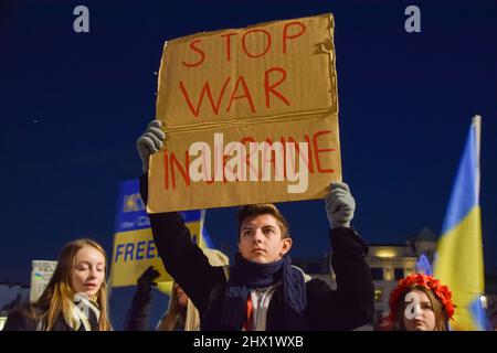 Londra, Inghilterra, Regno Unito. 8th Mar 2022. Un giovane uomo protester detiene un segno fatto di cartone, dicendo "Guerra di arresto in Ucraina”, accanto a lui è una giovane donna con un pezzo di testa di fiore arancione e numerose ormai molto familar bandiere ucraine di blu e giallo. Migliaia di persone si sono radunate a Trafalgar Square per il quattordicesimo giorno di proteste, mentre la Russia continua la sua guerra in Ucraina. (Credit Image: © Vuk Valcic/ZUMA Press Wire) Foto Stock