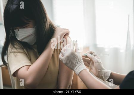 Giovane ragazza asiatica vaccinare con il medico dando colpo a paziente di bambino, il concetto di iniezione di vaccino di Covid-19 Foto Stock