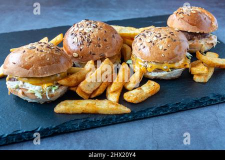 Primo piano di gustose patatine fritte e appetitosi hamburger su un tabellone nero Foto Stock