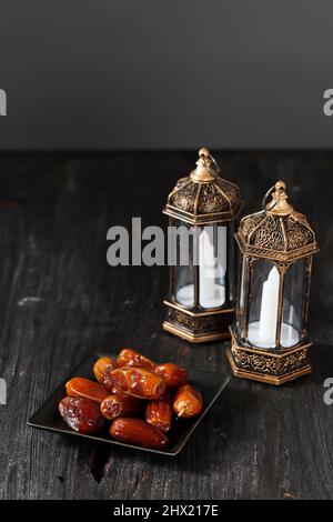 Lanterna di fuoco selezionata e date su tavola di legno. Concetto di festa di Ramadan kareem, spazio di copia per il testo. Focus su frutta datteri Foto Stock