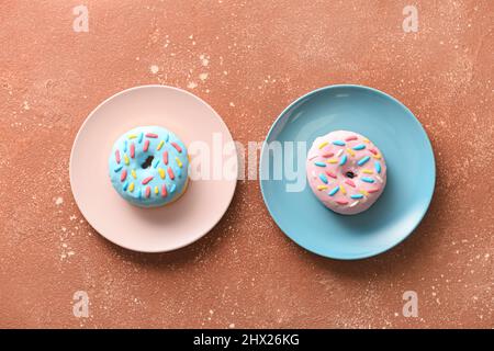 Piatti con deliziose ciambelle su sfondo colorato Foto Stock