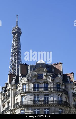 la Torre Eiffel che si erge direttamente sopra un classico edificio residenziale parigino in stile Haussmann lungo l'Avenue de la Bourdonnais nel 7° arrondissement Foto Stock