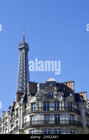 la Torre Eiffel che si erge direttamente sopra un classico edificio residenziale parigino in stile Haussmann lungo l'Avenue de la Bourdonnais nel 7° arrondissement Foto Stock
