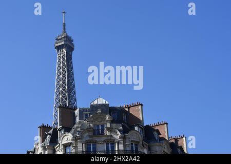 la Torre Eiffel che si erge direttamente sopra un classico edificio residenziale parigino in stile Haussmann lungo l'Avenue de la Bourdonnais nel 7° arrondissement Foto Stock