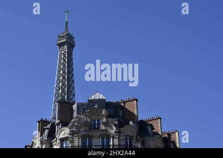 la Torre Eiffel che si erge direttamente sopra un classico edificio residenziale parigino in stile Haussmann lungo l'Avenue de la Bourdonnais nel 7° arrondissement Foto Stock