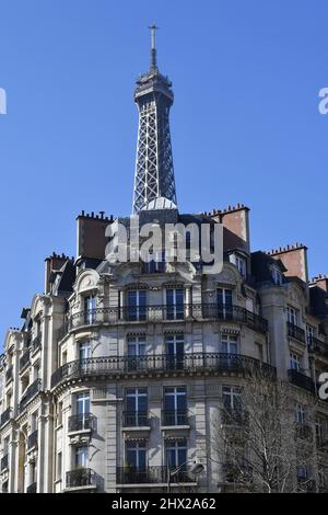 la Torre Eiffel che si erge direttamente sopra un classico edificio residenziale parigino in stile Haussmann lungo l'Avenue de la Bourdonnais nel 7° arrondissement Foto Stock