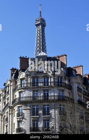 la Torre Eiffel che si erge direttamente sopra un classico edificio residenziale parigino in stile Haussmann lungo l'Avenue de la Bourdonnais nel 7° arrondissement Foto Stock