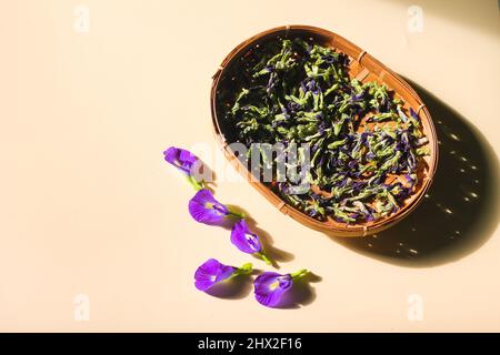 Bunga Telang Kering o Pea di Farfalle essiccata Fiori su piastra di bambù intrecciata. Sfondo isolato. Foto Stock