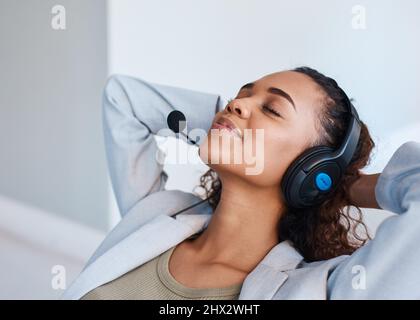 Una giovane donna con cuffia si inclina all'indietro e fa una pausa durante la giornata di lavoro Foto Stock