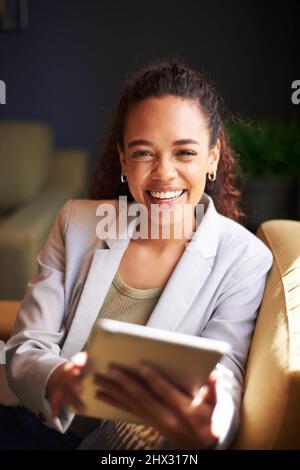 Una giovane donna d'affari tiene la sua tavoletta seduta alla luce del sole del pomeriggio Foto Stock