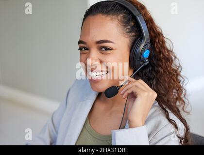 Un agente del call center tiene il microfono della cuffia più vicino al viso e sorride Foto Stock