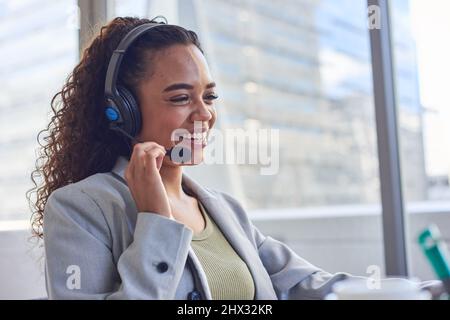 Un giovane agente tiene il microfono della cuffia e sorride- grattacielo Foto Stock