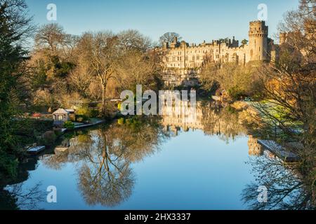 17 gennaio 2022: Warwick Castle, Warwickshire, Regno Unito - Warwick Castle si riflette nel fiume Avon in una bella giornata invernale soleggiata con cielo blu chiaro. Foto Stock