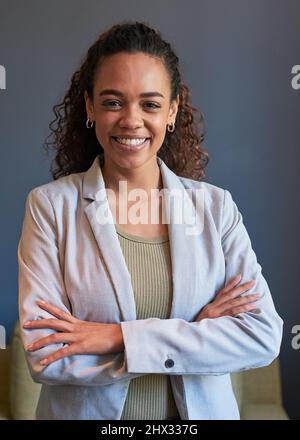 Una giovane donna d'affari si alza con le braccia incrociate in una posa ritratto Foto Stock