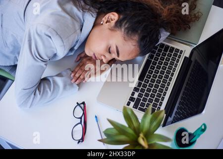 Una vista dall'alto di una donna esausta che dorme sulla sua scrivania in ufficio Foto Stock