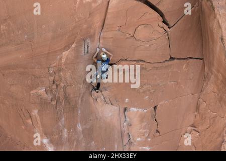 Una femmina scalatore di piombo raggiunge la parte superiore del percorso chiamato i fiocchi di Wrath su Wall Street vicino a Moab, Utah. Foto Stock