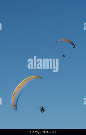 Due parapendio motorizzati in aria in inverno su South Padre Island, Texas. Su un parapendio motorizzato, il pilota indossa un motore zaino. Foto Stock