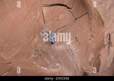 Una femmina scalatore di piombo raggiunge la parte superiore del percorso chiamato i fiocchi di Wrath su Wall Street vicino a Moab, Utah. Foto Stock