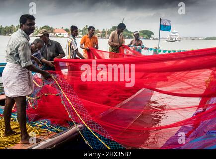 I pescatori tendono alle loro barche da pesca e reti. Fotografato in Kerala, India Foto Stock