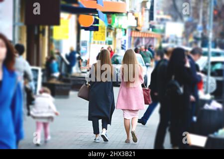 Due ragazze vestite alla moda camminano per la strada della città. Foto Stock
