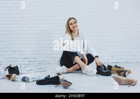 Eleganti scarpe bionda da mentre si siede sul pavimento. Vista laterale di un sacco di scarpe da donna sul pavimento, una scelta di scarpe eleganti. Foto Stock